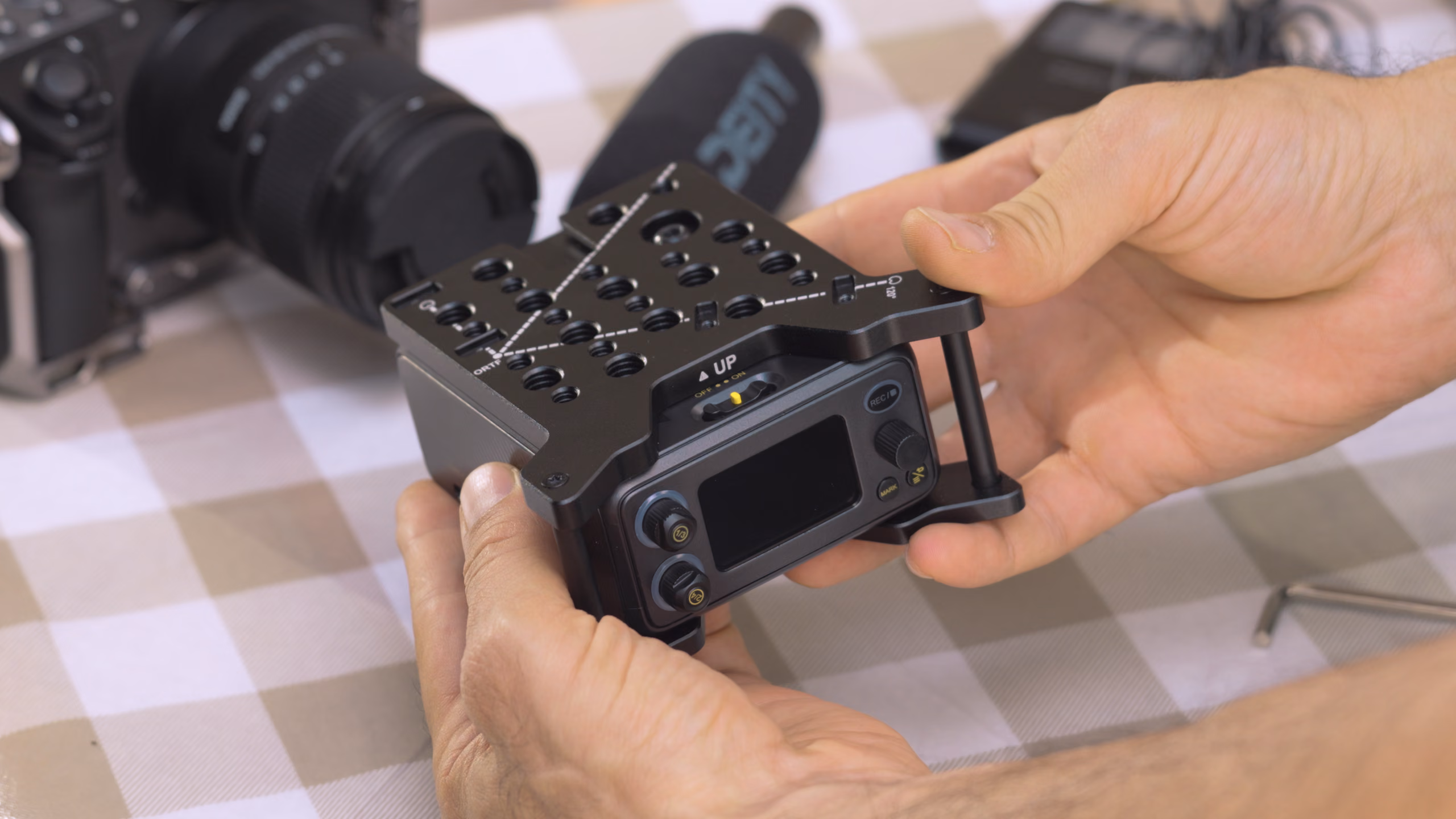 Hands holding the PR-4 in its cage next to a camera