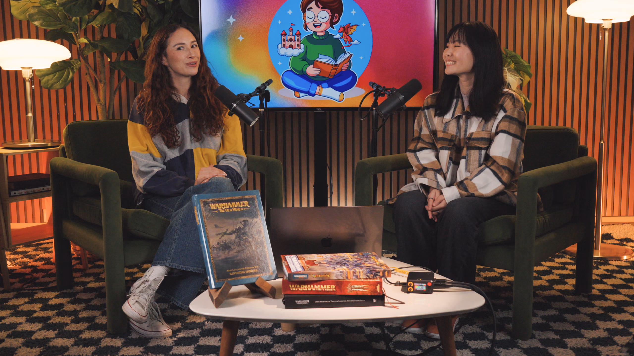 Two hosts recording a conversation on a studio set, PR-4 on the table between them