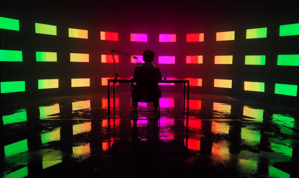 RGB color LED wall infront of a gaming desk showing a twitch streamer using a podcast microphone